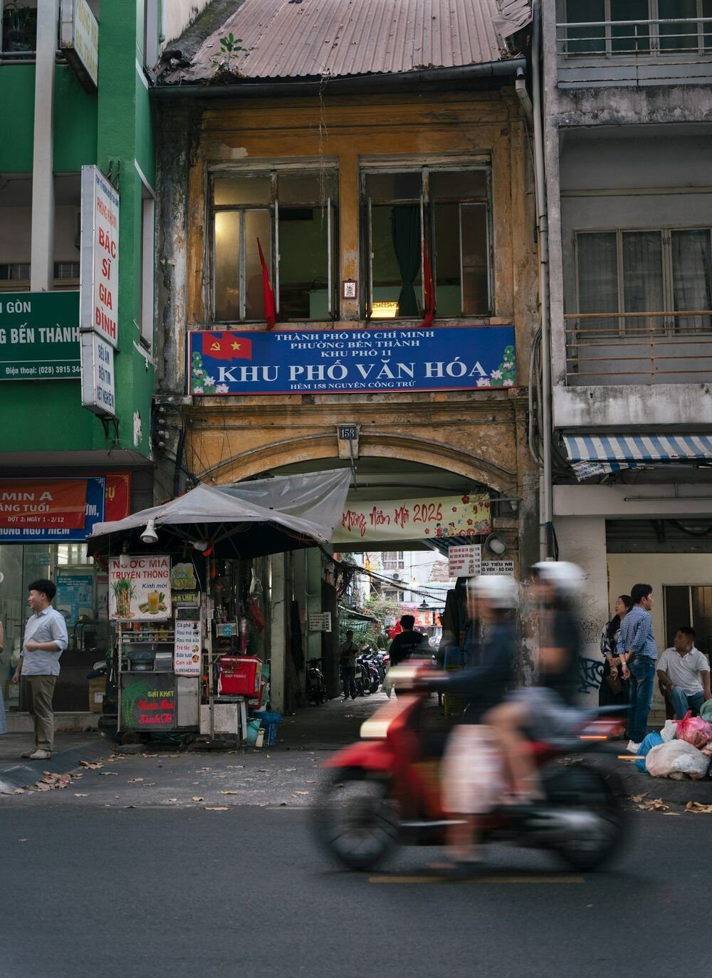 Chiếc xe máy màu đỏ nhòe vì chuyển động chạy ngang một quầy hàng trước ngôi nhà cũ ở TP. Hồ Chí Minh